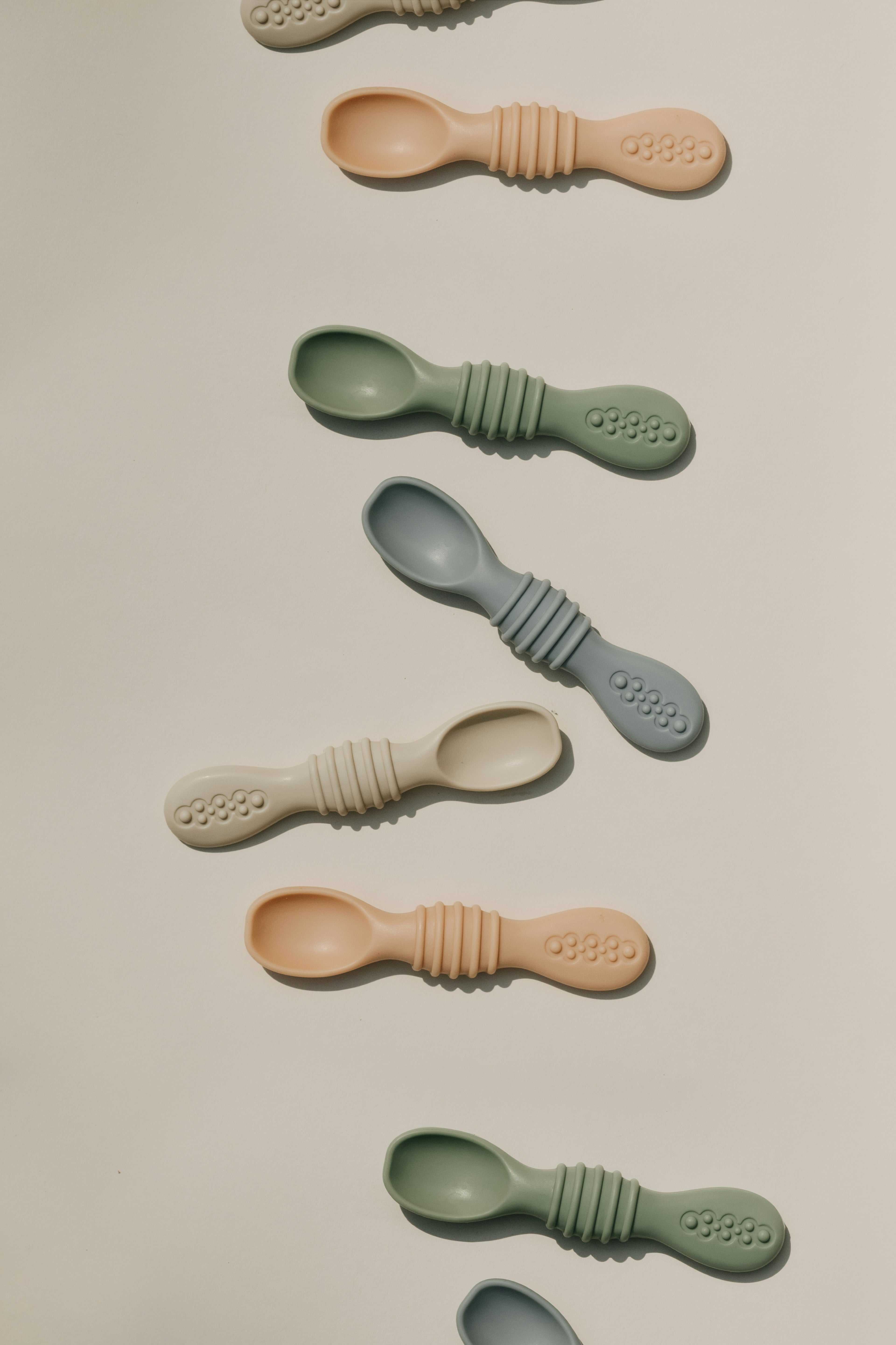 Set of four silicone baby first spoons in muted colours