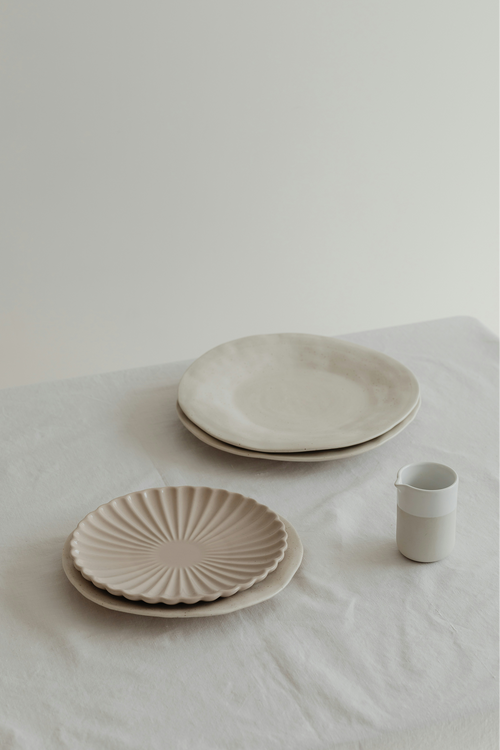 Hand-thrown fluted plates and small espresso cup on linen