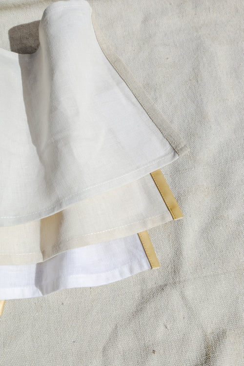 Folded linen napkins with subtle ribbon detail on the hem