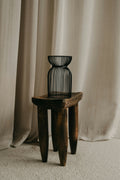 Small ribbed smoked black glass vase on a wooden stool