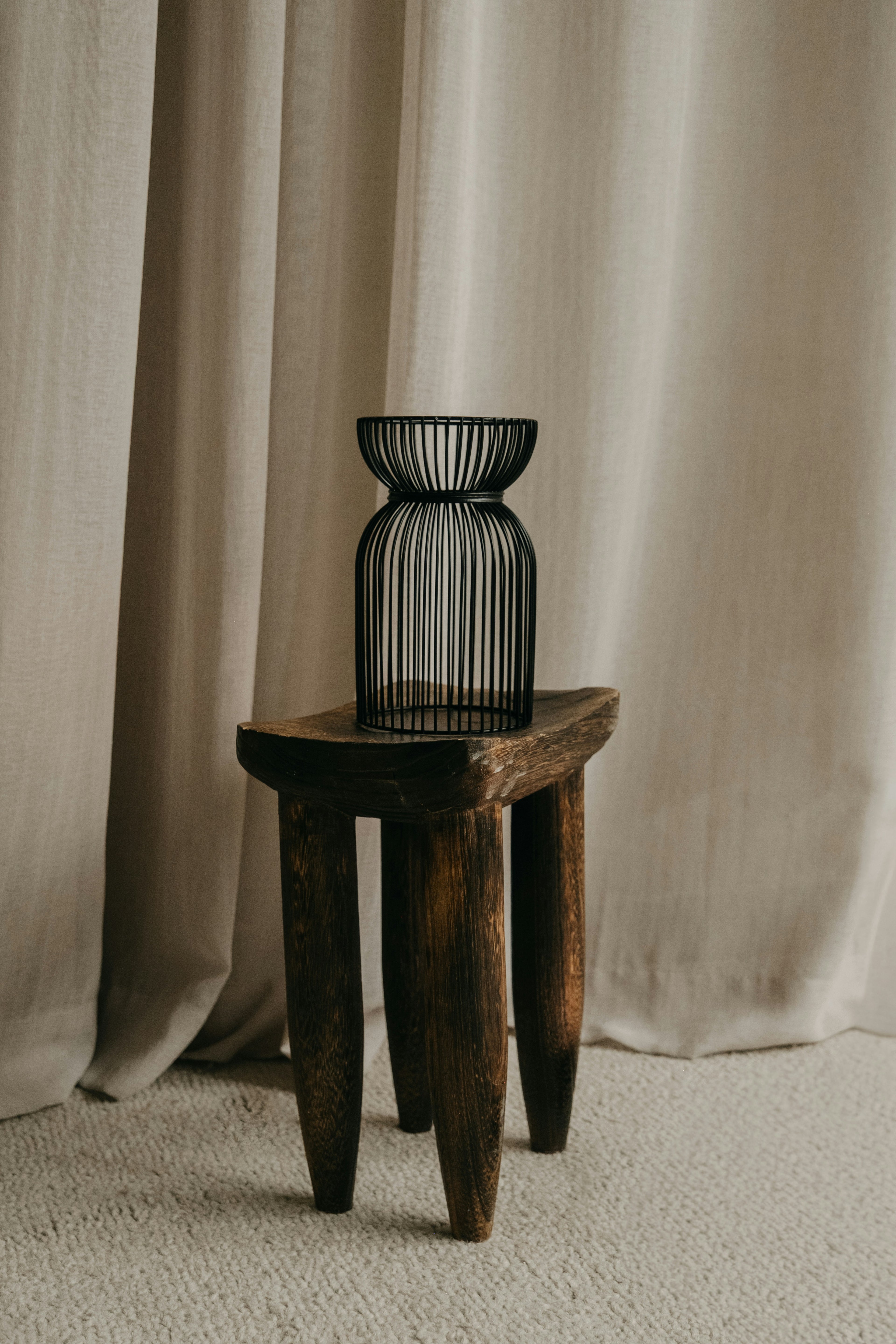 Small ribbed smoked black glass vase on a wooden stool