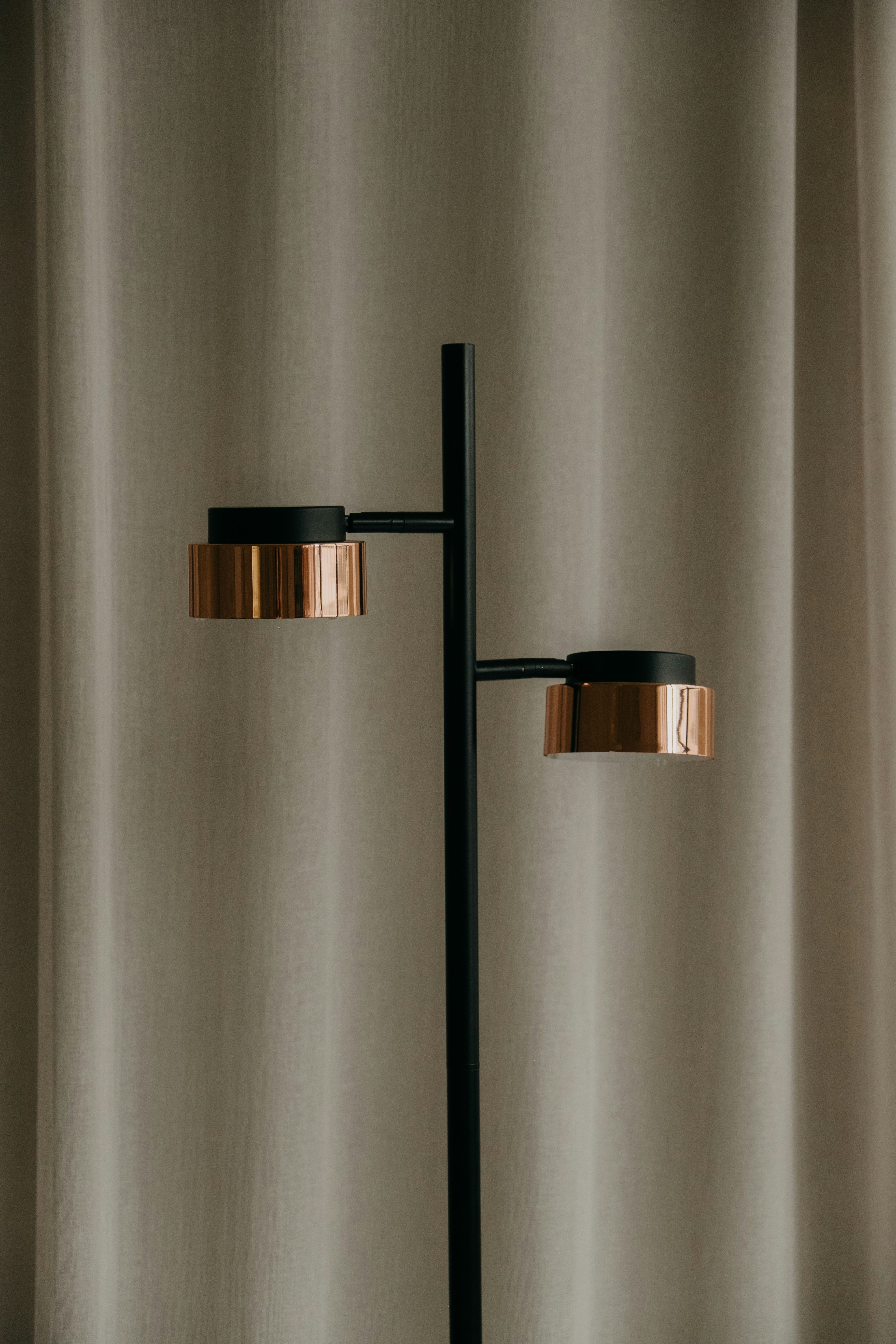 Modern floor lamp with two warm-light brass discs on a slim black frame