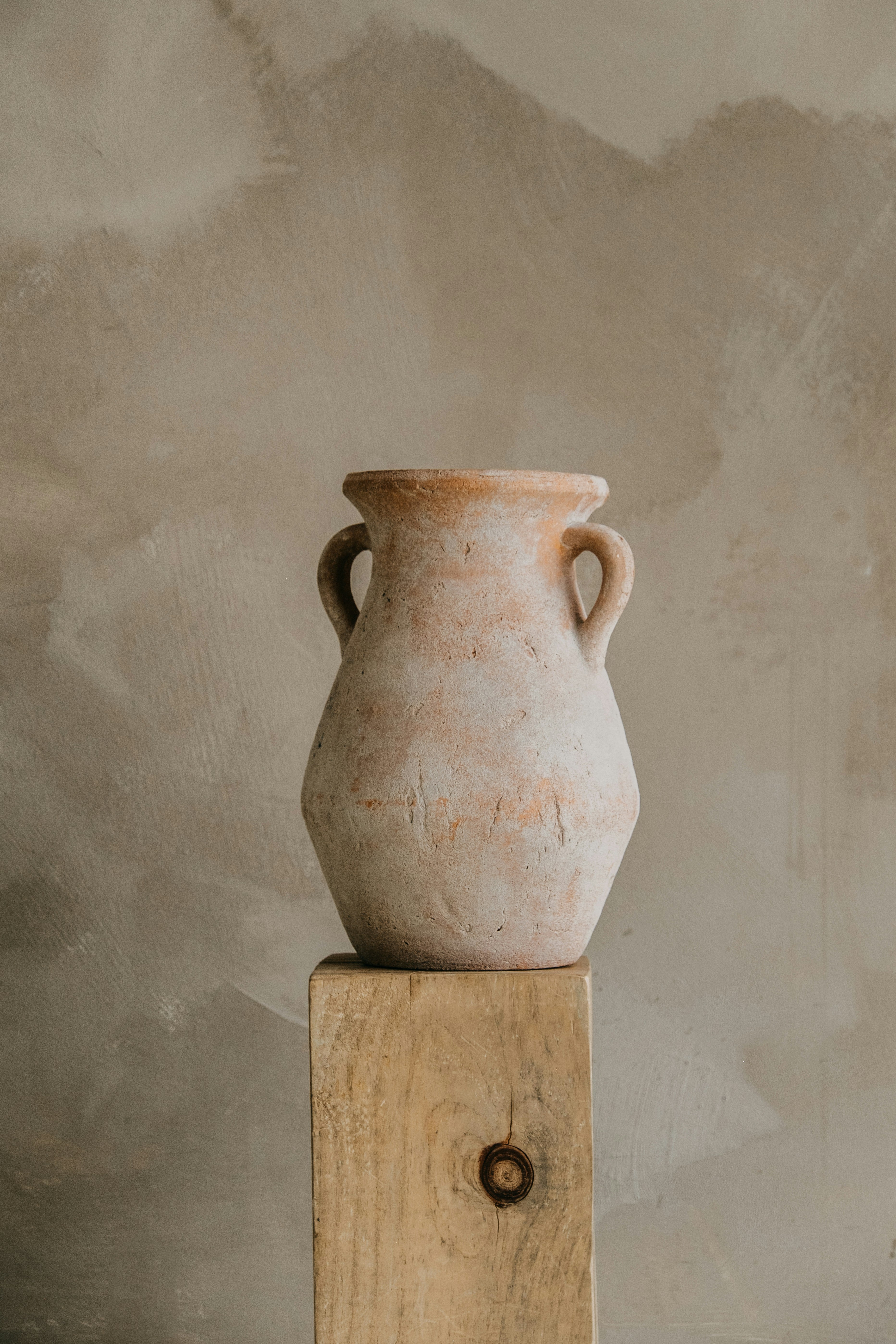 Hand-finished terracotta amphora vase on a wooden pedestal