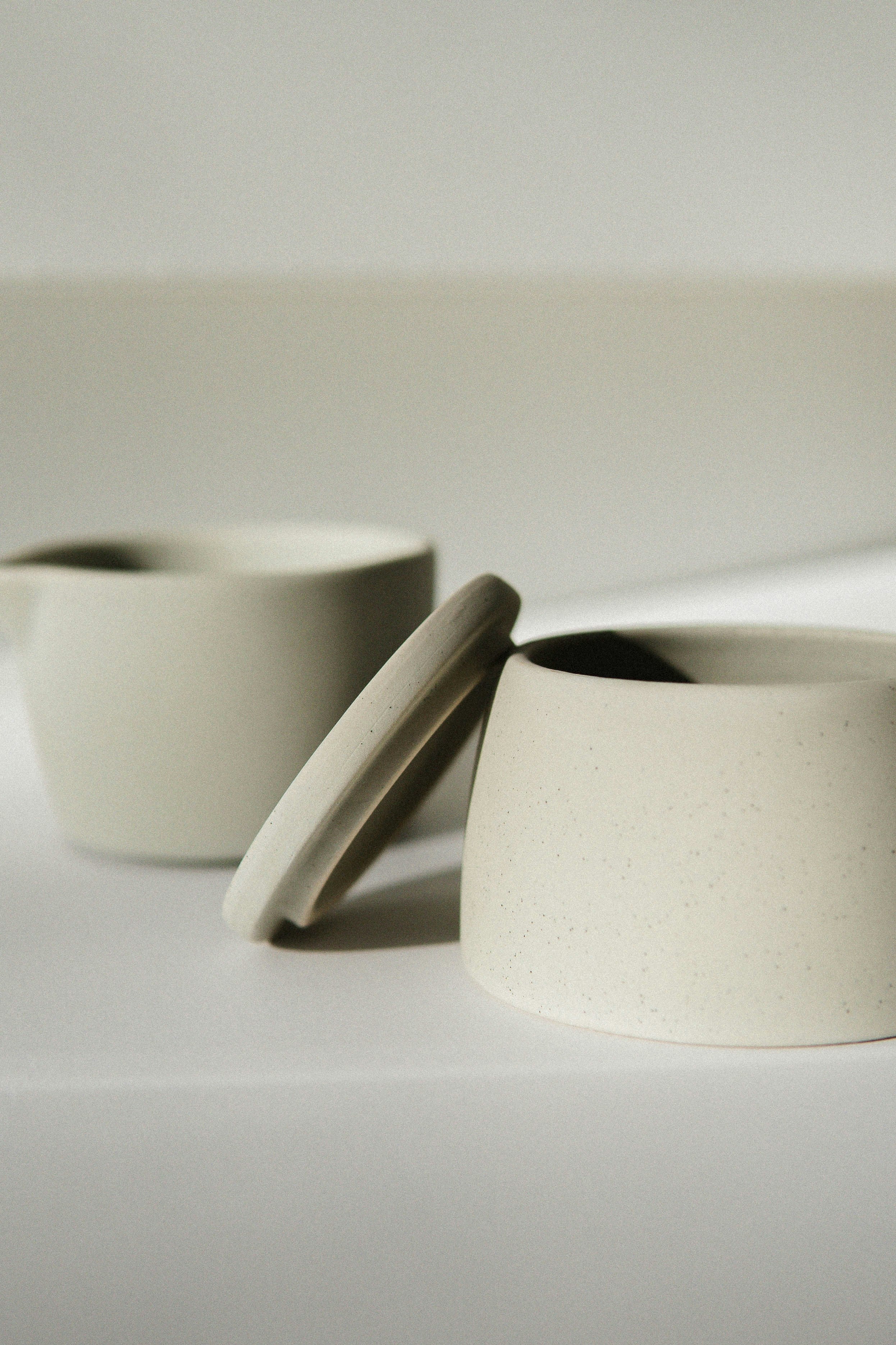 Pair of matte cream stoneware mugs with hand-fitted lids