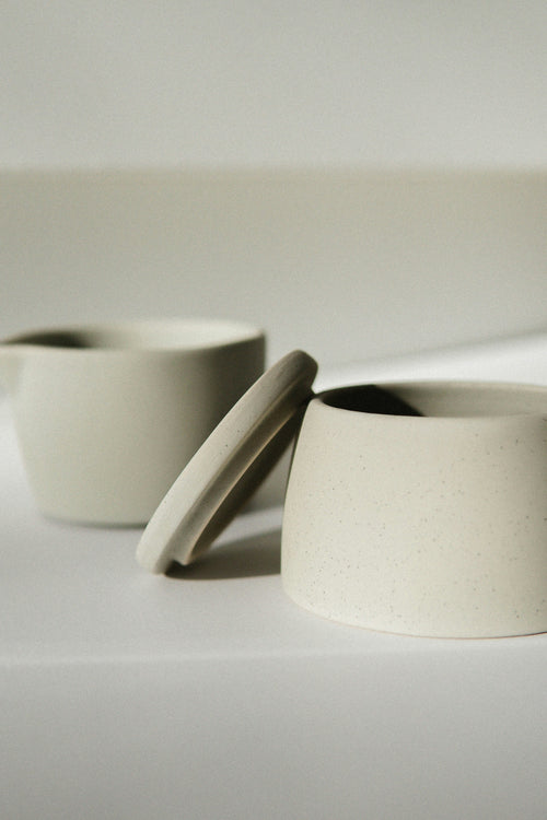 Pair of matte cream stoneware mugs with hand-fitted lids