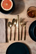 Brushed brass silverware place setting on a wooden table