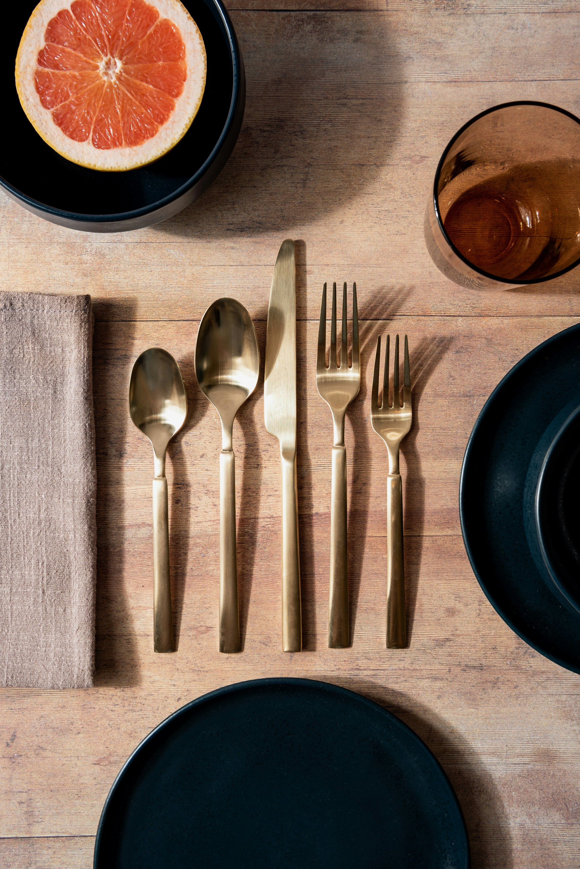 Brushed brass silverware place setting on a wooden table